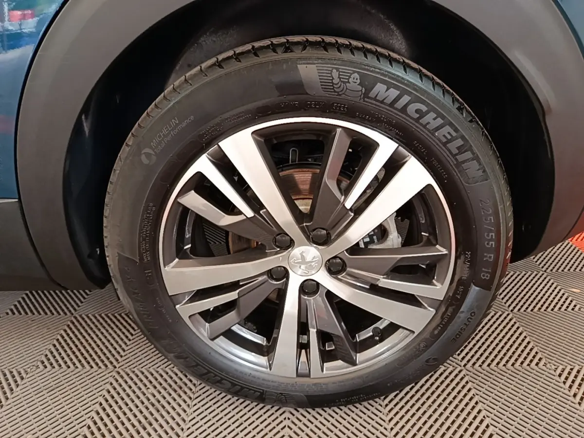 Gros plan sur la roue avant droite du Peugeot 3008 bleu, mettant en valeur la jante alliage et le pneu Michelin.