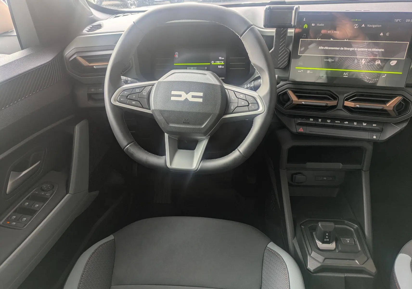 Vue intérieure centrée sur le volant et tableau de bord du Dacia Duster Hybrid 155 Extreme, avec écran tactile et commandes au volant.