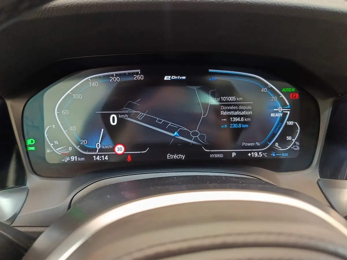 Tableau de bord numérique de BMW Série 3 320e hybride, affichage vitesse, navigation et état batterie.
