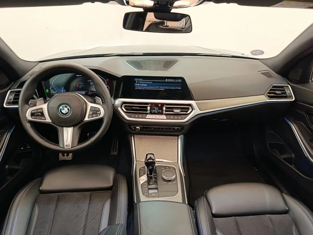 Vue intérieure avant de la BMW Série 3 320e M Sport 2022, tableau de bord moderne avec écran tactile et volant cuir noir.