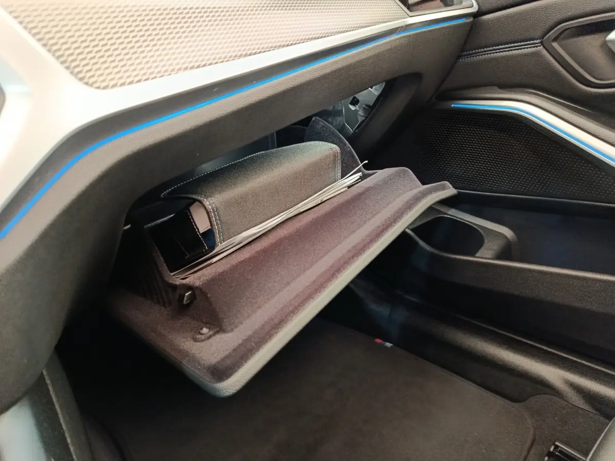 Vue intérieure côté passager de la BMW Série 3 320e M Sport 2022, boîte auto, avec boîte à gants ouverte et éclairage d’ambiance bleu.
