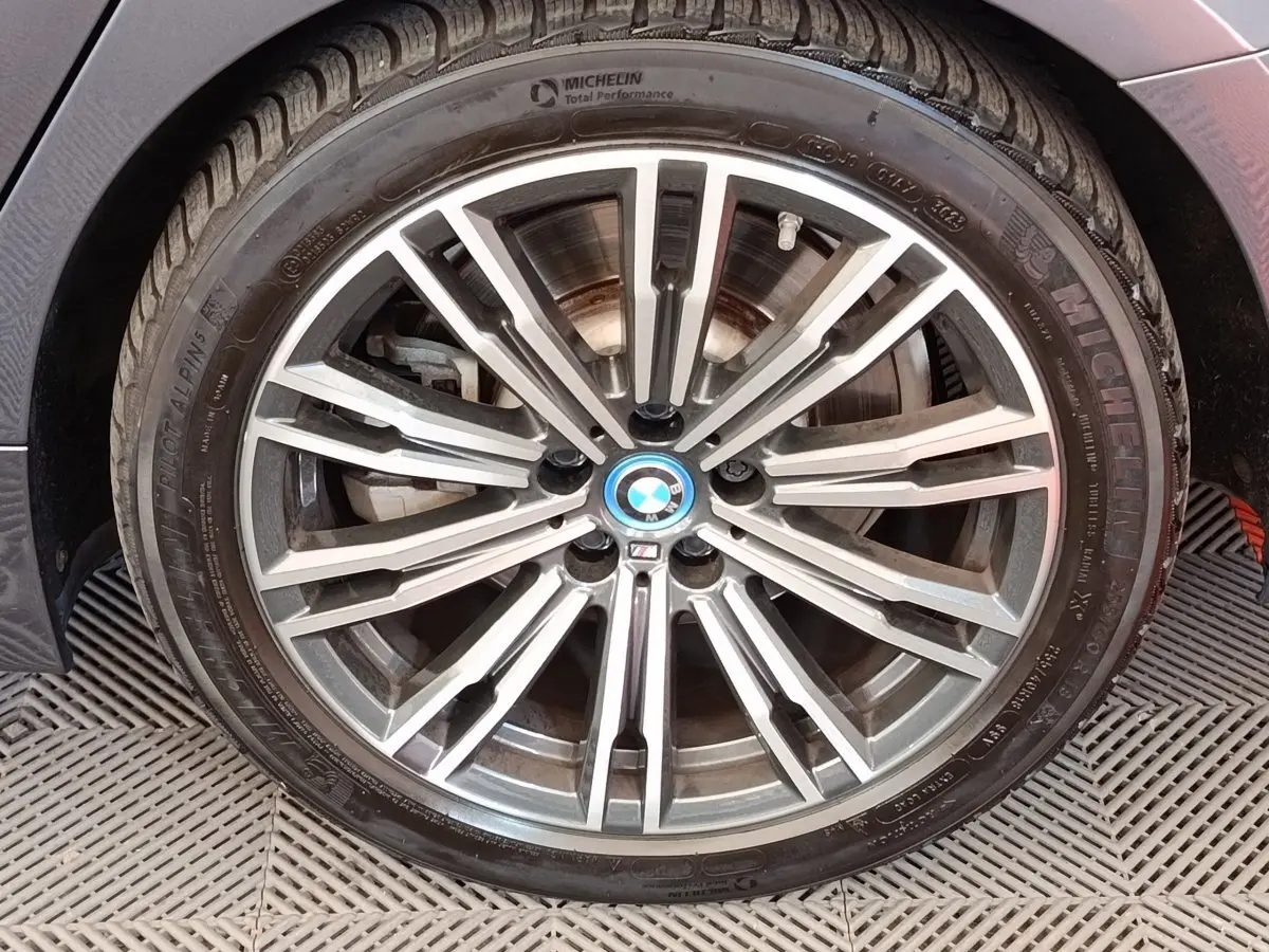 Gros plan sur la jante alliage BMW M Sport gris clair avec logo bleu au centre sur pneu Michelin.