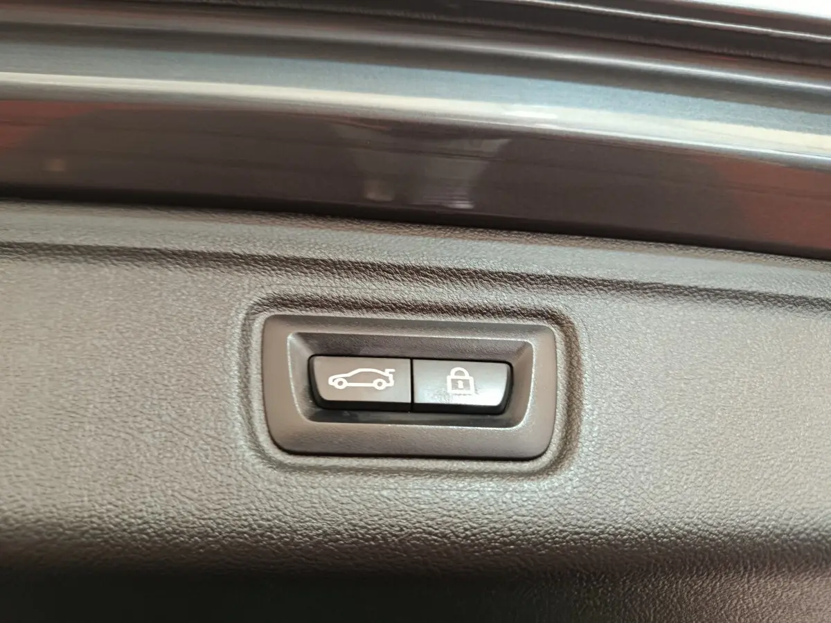 Gros plan sur les boutons d'ouverture et de verrouillage du coffre d'une BMW Série 3 gris foncé, intérieur du hayon.