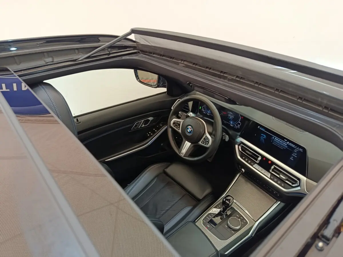 Vue intérieure côté conducteur d'une BMW Série 3 320e gris foncé, avec tableau de bord numérique et volant cuir multifonctions.
