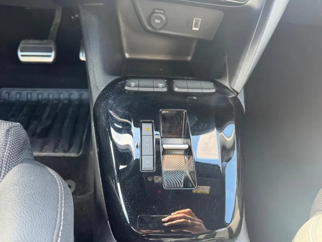 Gros plan sur la console centrale noire brillante de l’Opel Corsa 2025, montrant la commande de boîte automatique et les boutons de contrôle.