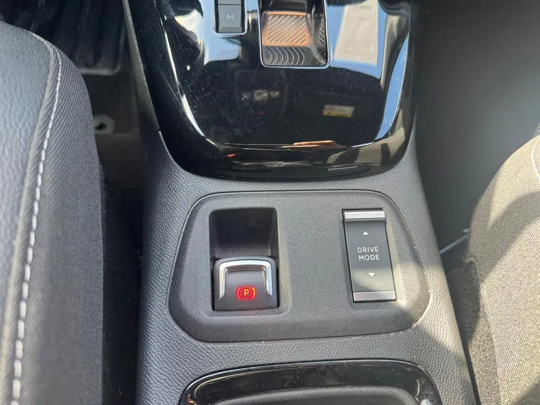 Gros plan sur la console centrale de l’Opel Corsa noire 2025, montrant le frein à main électronique et le bouton Drive Mode.