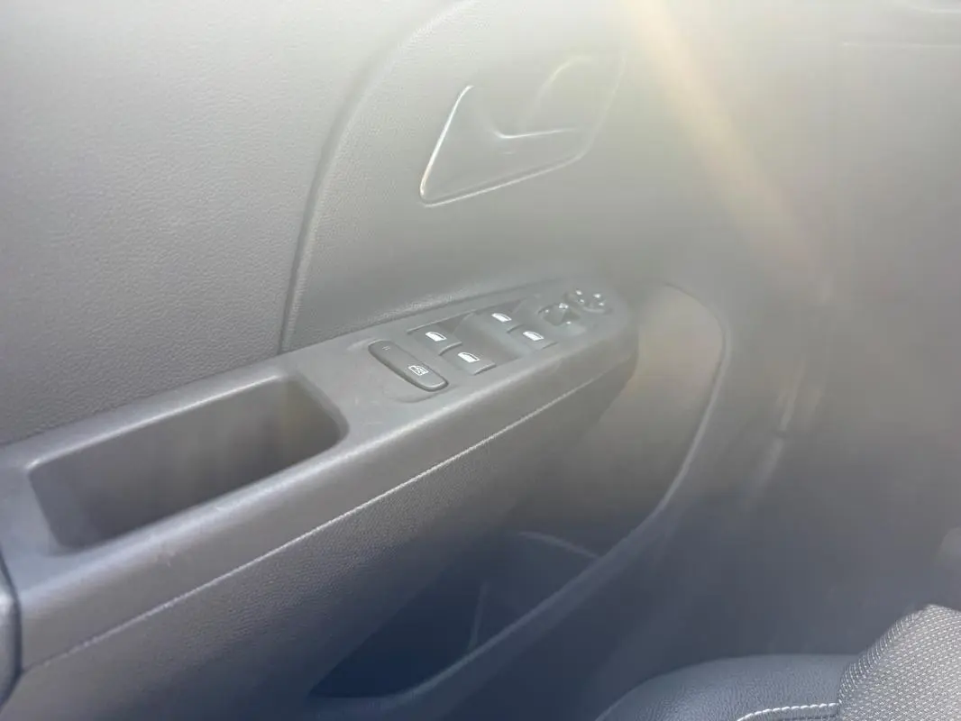 Gros plan sur la porte côté conducteur de l’Opel Corsa 1.2 Turbo Hybrid 2025 avec commandes de vitres et poignée noire.