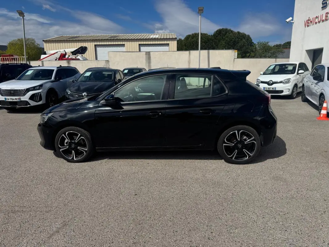 Opel Corsa 1.2 Turbo Hybrid 2025 vue de profil côté gauche, finition noire brillante avec jantes noires et argentées.