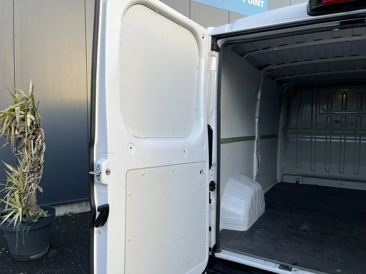 Vue arrière côté droit d’un Opel Movano Fourgon blanc 2024 avec porte latérale ouverte montrant l’intérieur vide du coffre.
