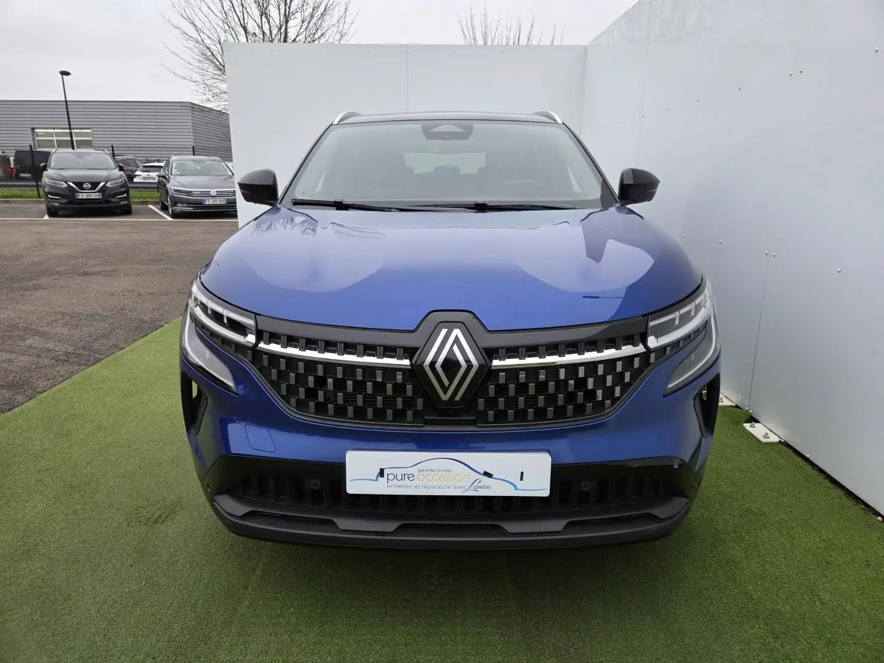 Vue de face du Renault Austral 2025 en bleu Iron avec toit noir, mettant en valeur la calandre à damier et les phares LED.