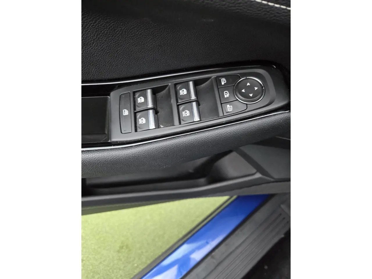 Gros plan sur les commandes des vitres et rétroviseurs côté conducteur du Renault Austral bleu Iron avec intérieur noir.