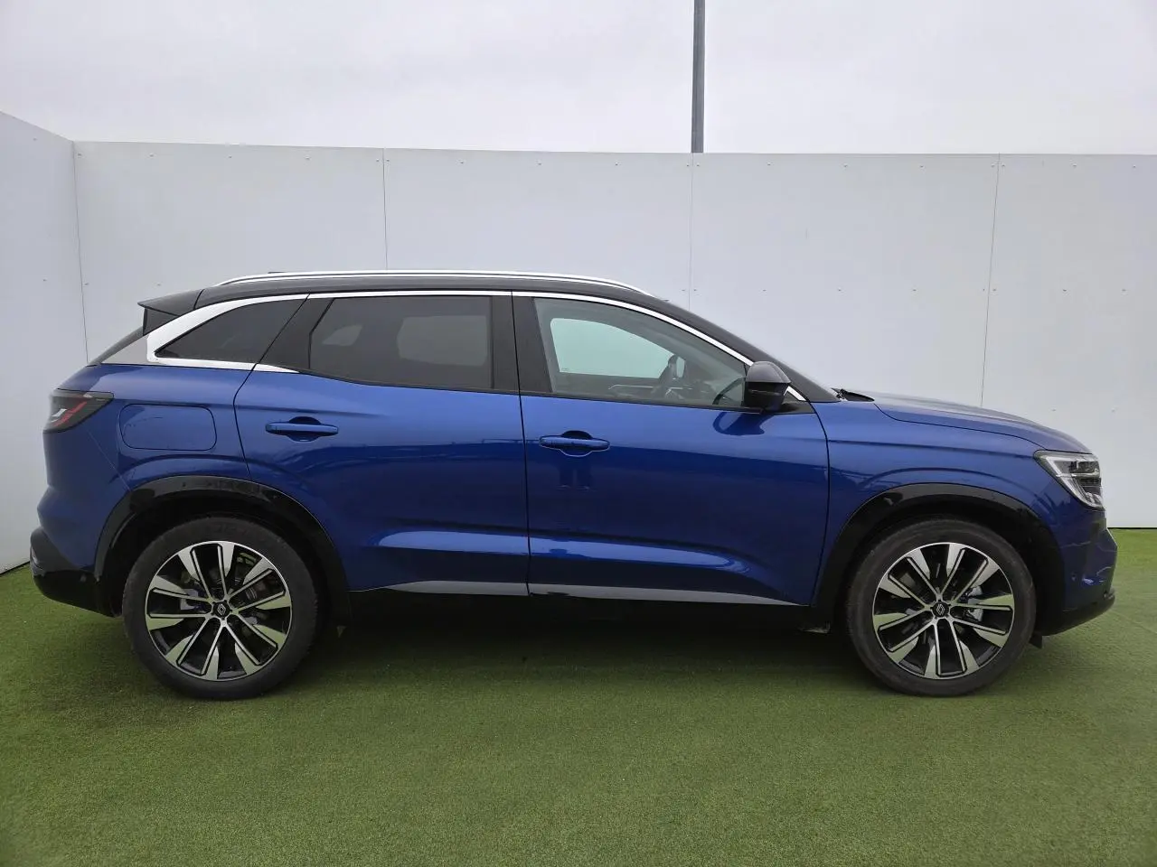 Renault Austral E-Tech hybride bleu Iron avec toit noir, vue de profil côté gauche sur fond neutre.