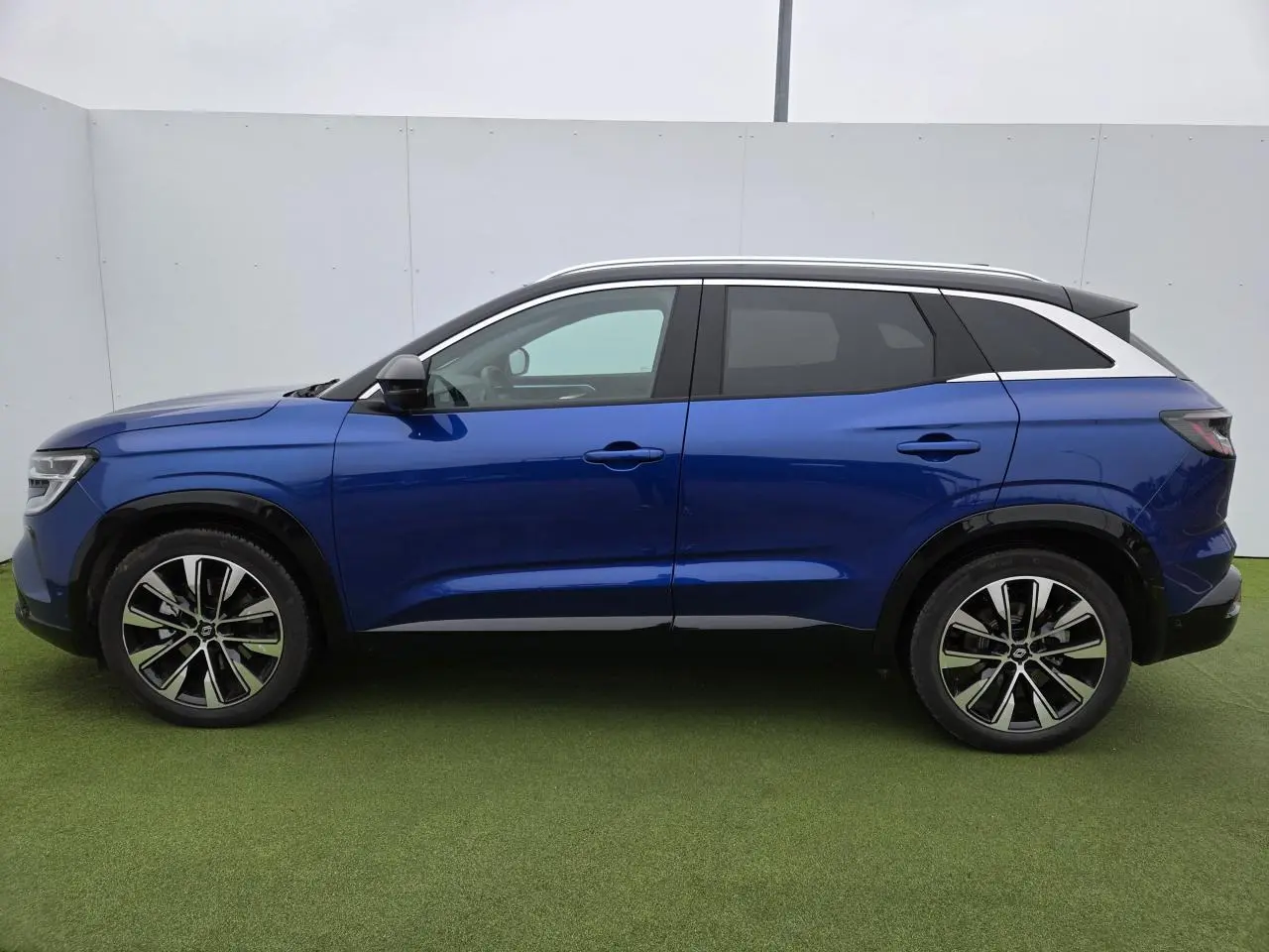 Profil côté gauche du Renault Austral 2025 en bleu Iron avec toit noir et jantes alliage noires diamantées.