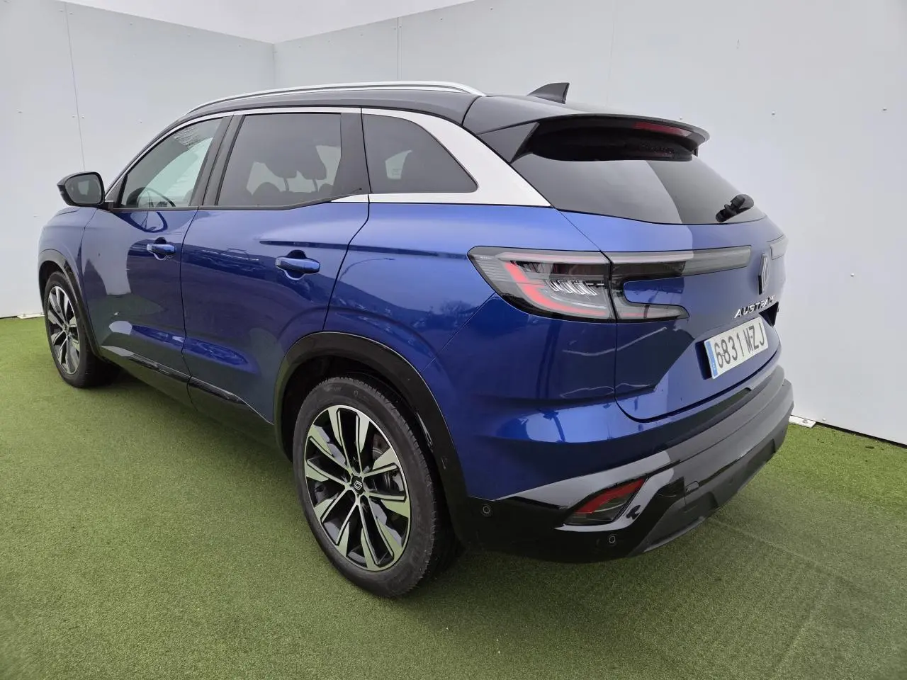 Renault Austral bleu Iron avec toit noir, vue 3/4 arrière droit, jantes alliage et feux arrière LED distinctifs.