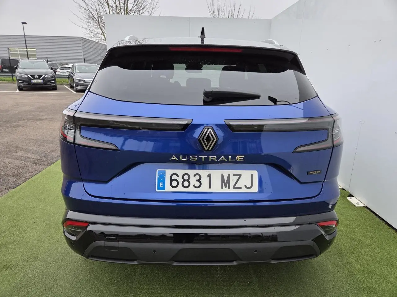 Vue arrière du Renault Austral bleu Iron avec toit noir, feux arrière allongés et logo central chromé.