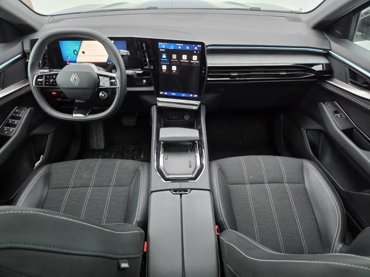 Vue intérieure avant du Renault Austral E-Tech 2025, tableau de bord moderne avec écran tactile vertical et volant compact noir.