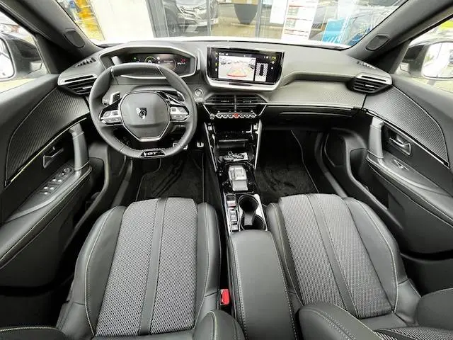 Vue intérieure avant du Peugeot 2008 blanc 2024, mettant en valeur le tableau de bord digital et la console centrale moderne.