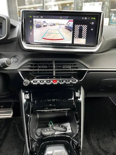 Vue intérieure du tableau de bord et console centrale du Peugeot 2008 blanc 2024, avec écran affichant la caméra de recul.