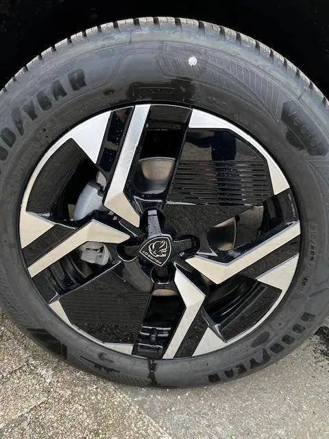 Gros plan sur la roue avant droite du Peugeot 2008 blanc 2024, jante alliage noire et argentée au design moderne.