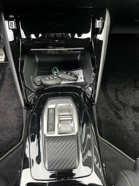 Vue plongeante sur la console centrale noire brillante du Peugeot 2008 GT 2024 avec boîte auto et clés posées.