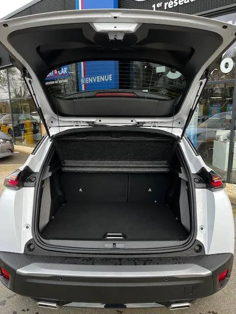 Vue arrière ouverte du coffre d’un Peugeot 2008 blanc 2024, avec hayon relevé et intérieur spacieux visible.