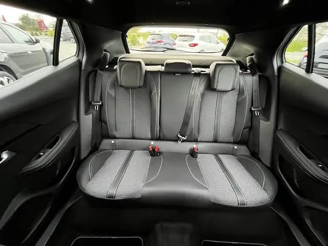 Vue intérieure arrière des sièges arrière noirs et gris du Peugeot 2008 PureTech 130 GT avec ceintures et appuis-tête visibles.