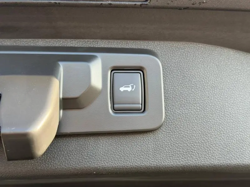 Bouton d'ouverture électrique du coffre sur panneau intérieur gris d'un Renault Scenic E-Tech 2025.