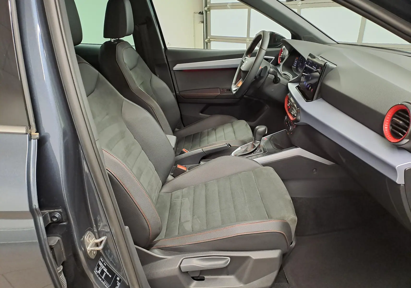 Vue intérieure côté conducteur du SEAT Arona 2024 gris magnétique, mettant en valeur les sièges sport et le tableau de bord moderne.