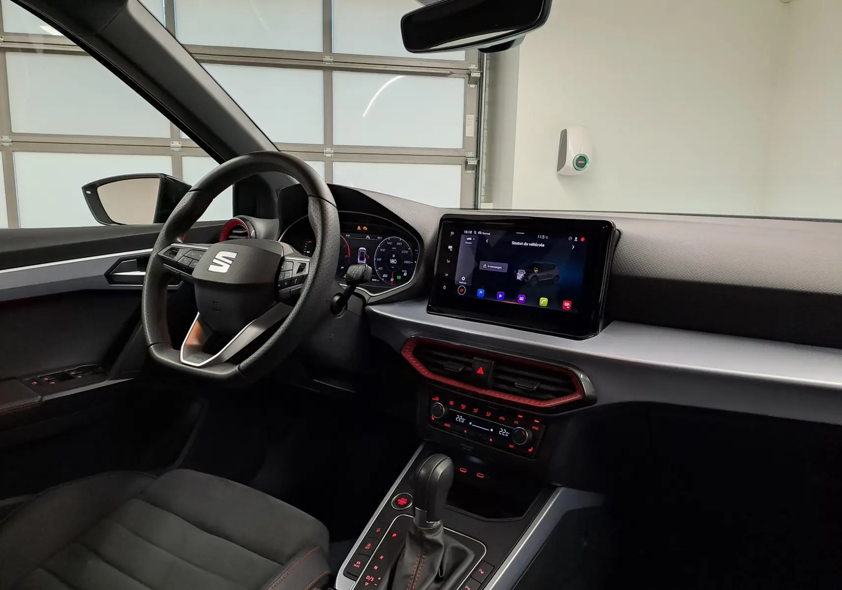 Vue intérieure côté conducteur du SEAT Arona 2024, tableau de bord moderne avec écran tactile et volant multifonction noir.