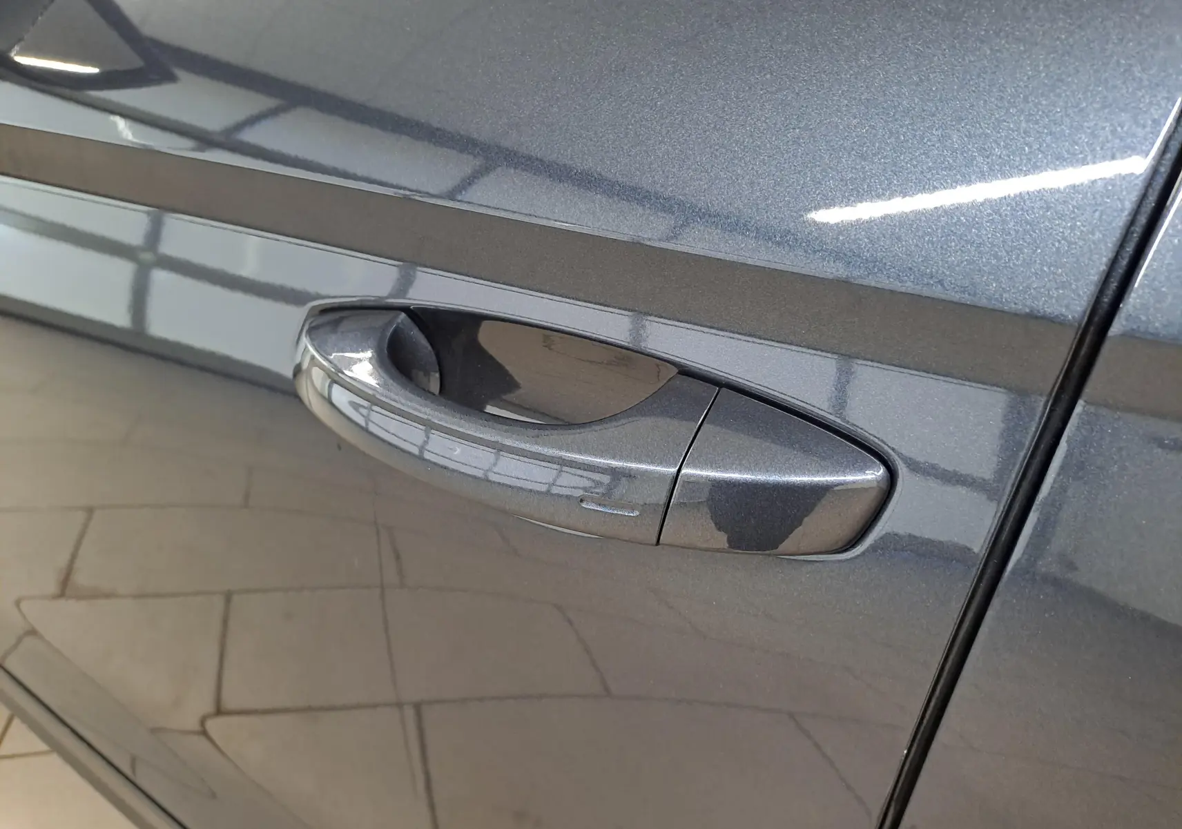 Poignée de porte côté gauche en gros plan sur SEAT Arona 2024 gris magnétique avec finition métallisée.