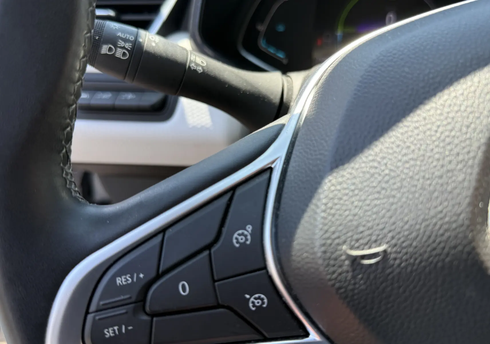 Gros plan sur la partie gauche du volant gris de la Renault Clio V 1.6 E-Tech Hybrid 2022 avec commandes de régulateur de vitesse.