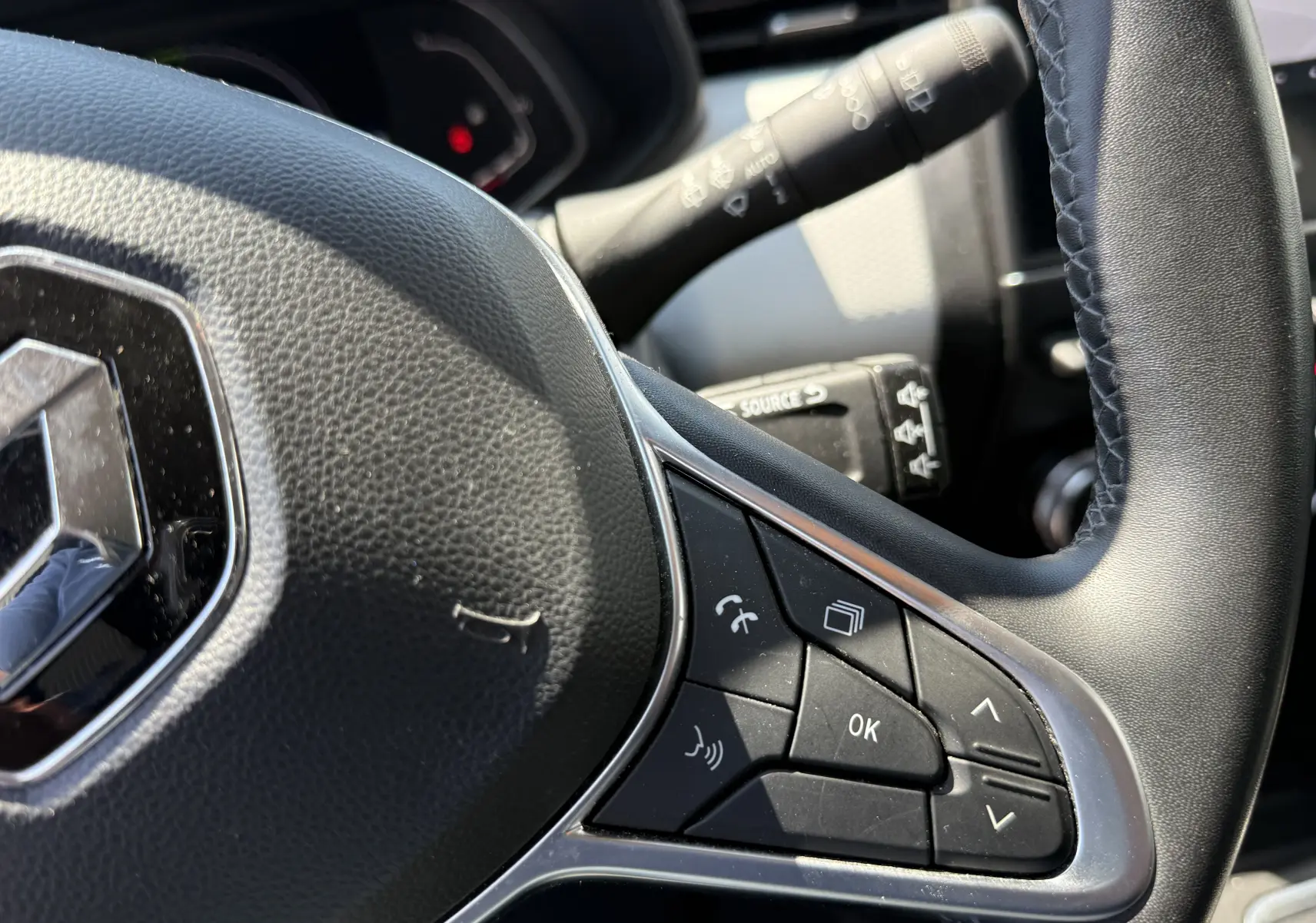 Gros plan sur le volant noir de la Renault Clio V gris, montrant les commandes multifonctions côté droit.