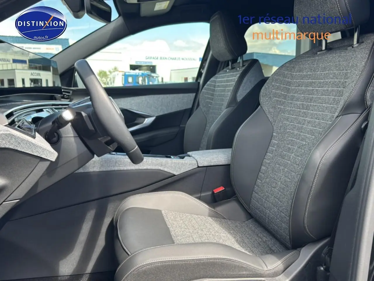 Vue intérieure côté conducteur du Peugeot 5008 Hybrid 145 allure 2025, sièges tissu gris et cuir noir.
