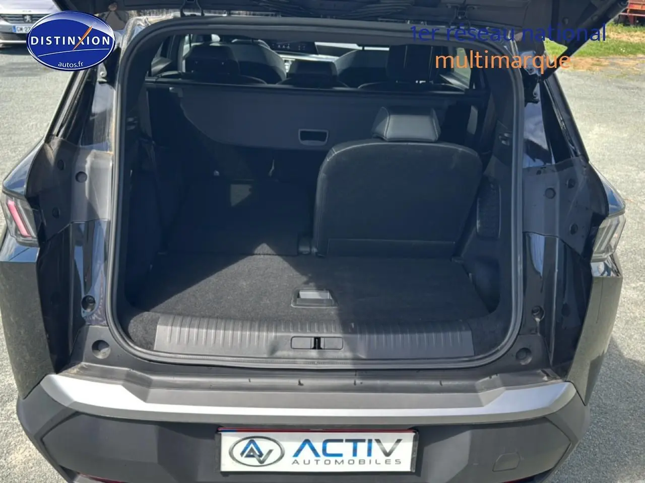 Coffre ouvert du Peugeot 5008 noir vu de l'arrière, montrant la banquette arrière partiellement rabattue et l'espace de chargement.