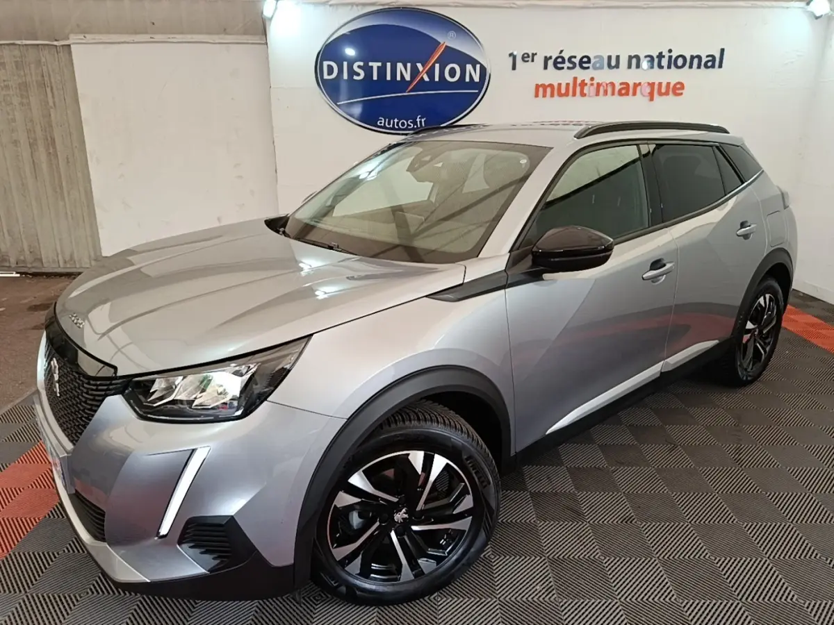 Peugeot 2008 gris clair vue 3/4 avant droit, avec jantes noires et rétroviseurs rabattables électriques.