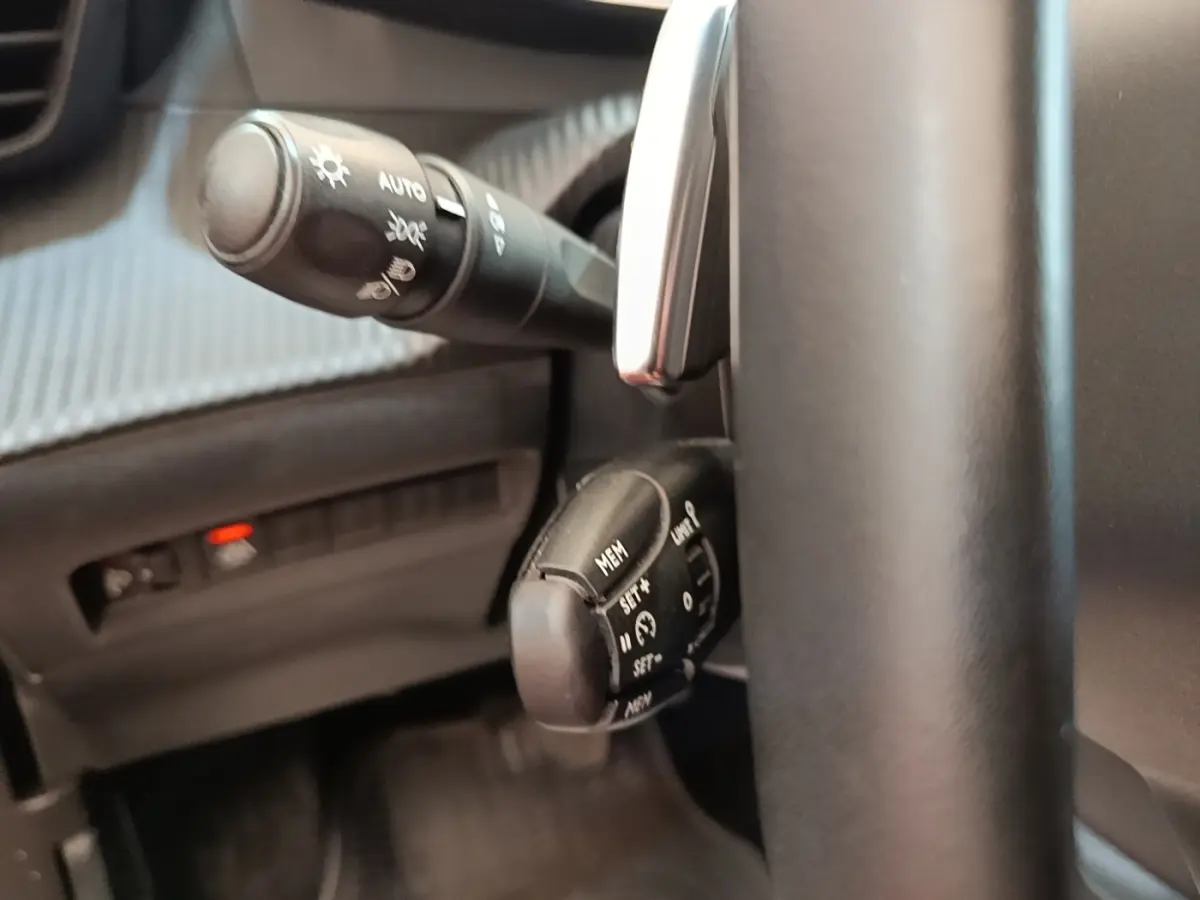 Gros plan sur le volant noir et les commandes de régulateur de vitesse du Peugeot 2008 gris clair, version Allure Pack 2022.