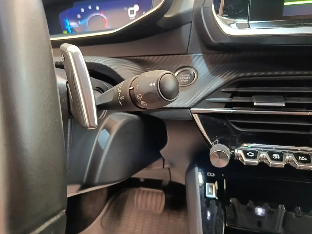 Gros plan intérieur côté conducteur du Peugeot 2008 2022, montrant la commande d’essuie-glace, bouton démarrage et partie du tableau de bord.
