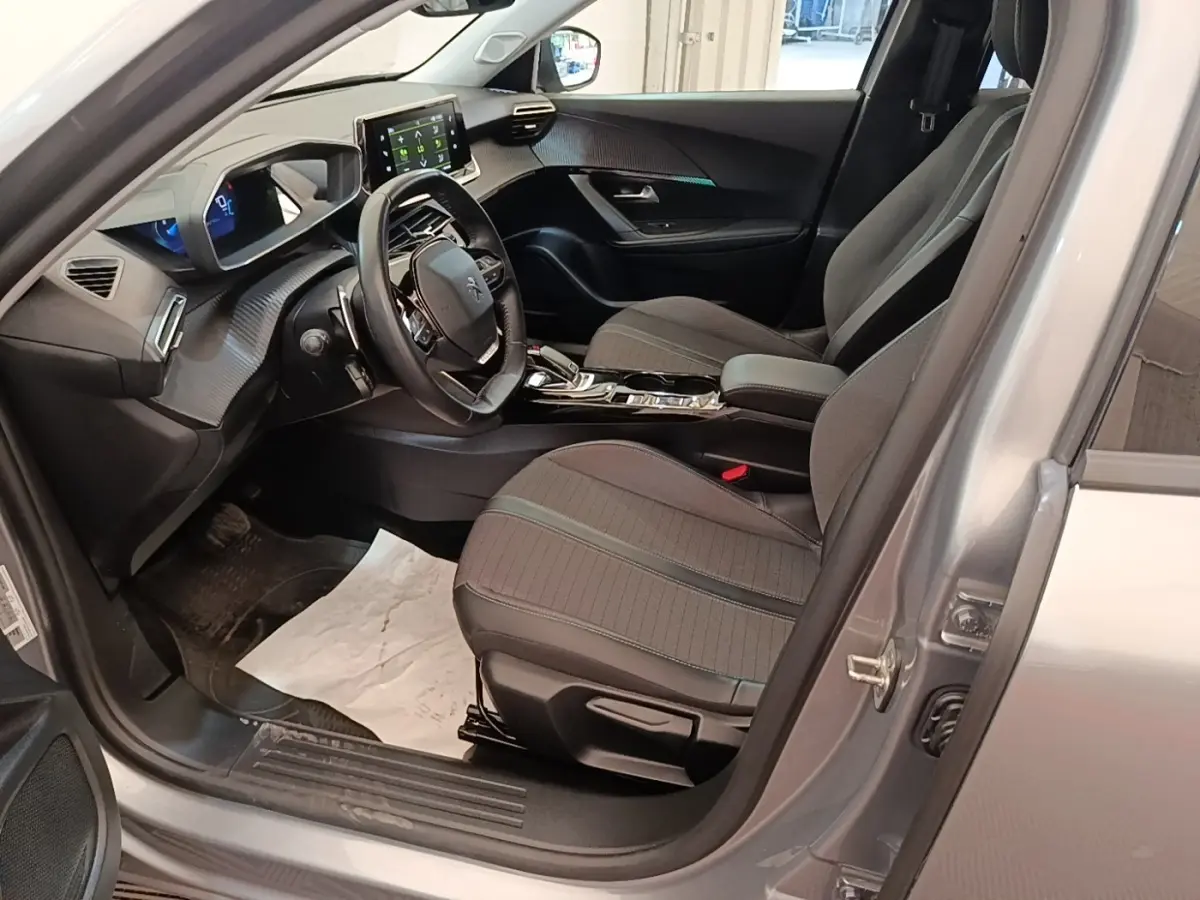 Intérieur avant droit d’un Peugeot 2008 gris clair 2022, avec tableau de bord numérique et écran tactile central.