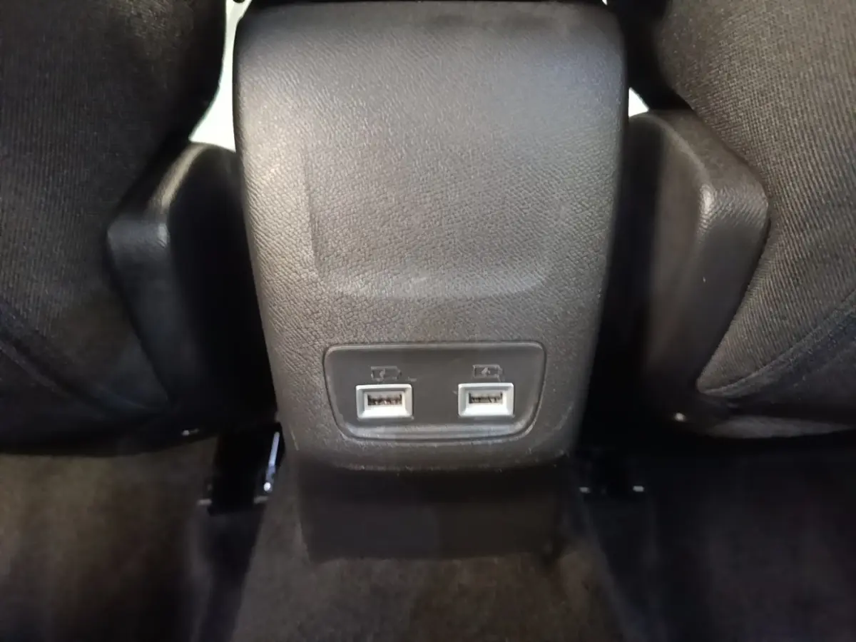 Gros plan sur la console centrale arrière noire du Peugeot 2008 gris clair, montrant deux ports USB pour les passagers arrière.