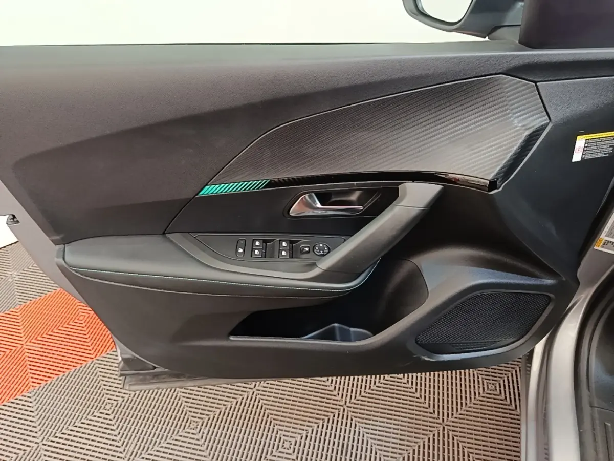 Vue intérieure côté gauche de la porte avant d’un Peugeot 2008 gris clair avec garniture noire et insert carbone.