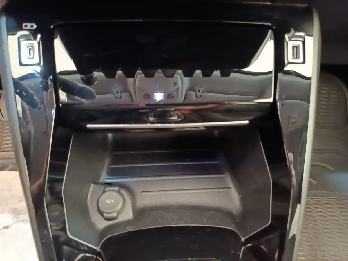 Gros plan sur la console centrale noire du Peugeot 2008 gris clair, avec prise 12V et ports USB visibles.