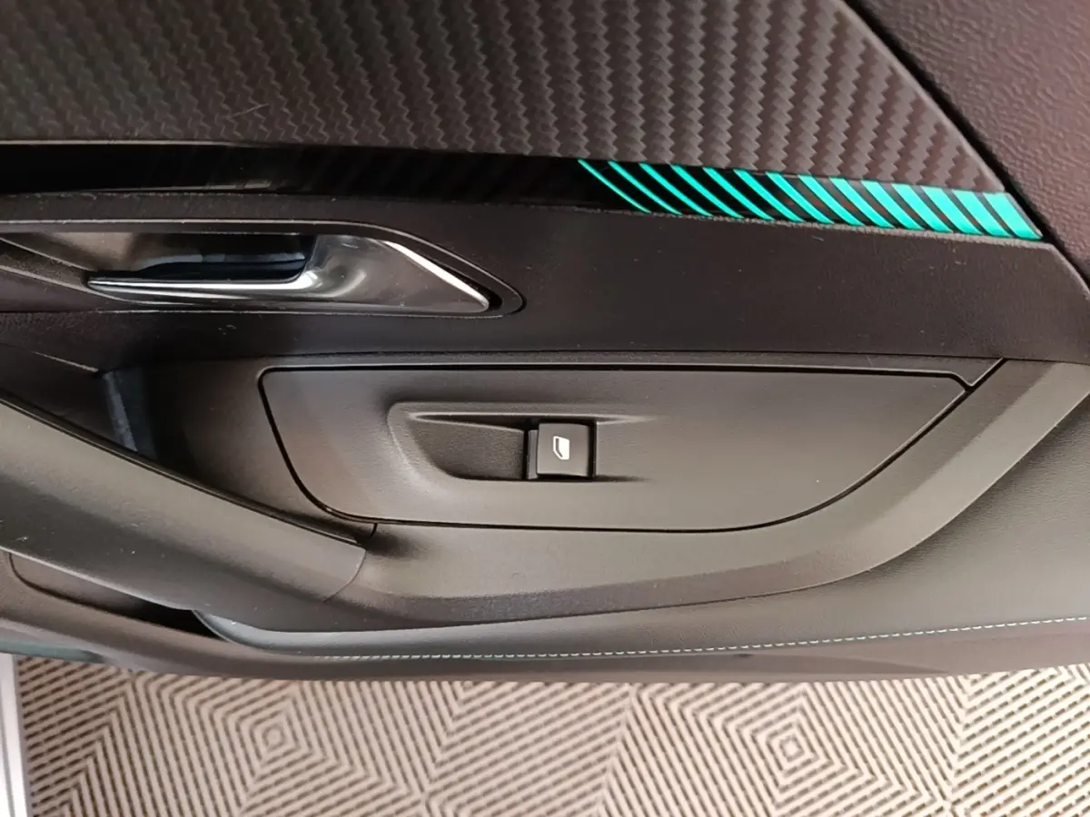 Détail de la porte côté gauche du Peugeot 2008 gris clair, avec bouton de commande de vitre et insert décoratif bleu.
