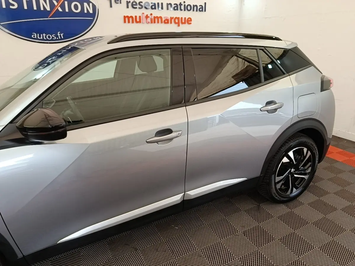 Vue côté gauche du Peugeot 2008 gris clair 2022 avec rétroviseurs noirs et jantes alliage noires.