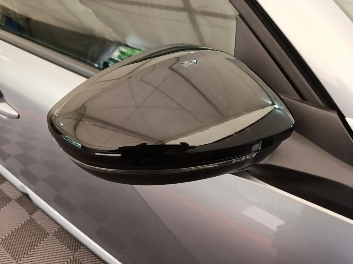 Rétroviseur extérieur noir en gros plan côté gauche sur Peugeot 2008 gris clair vue latérale.