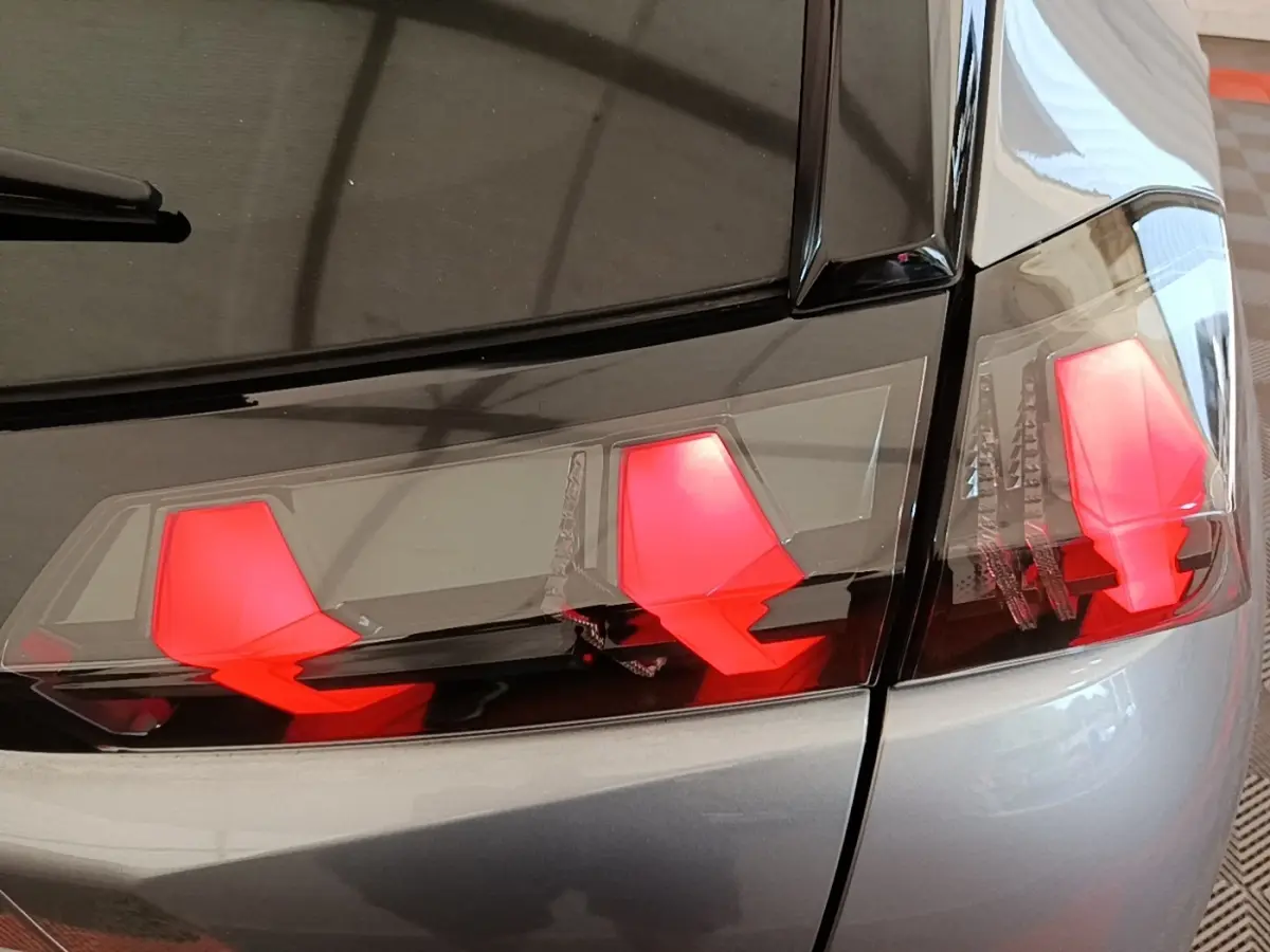 Gros plan sur les feux arrière rouges du côté gauche d’un Peugeot 2008 gris clair, finition Allure Pack 2022.