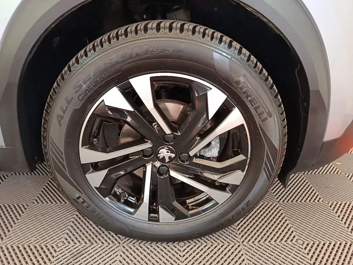 Gros plan sur la roue avant gauche gris clair du Peugeot 2008 avec jante alliage noire et argentée au design moderne.