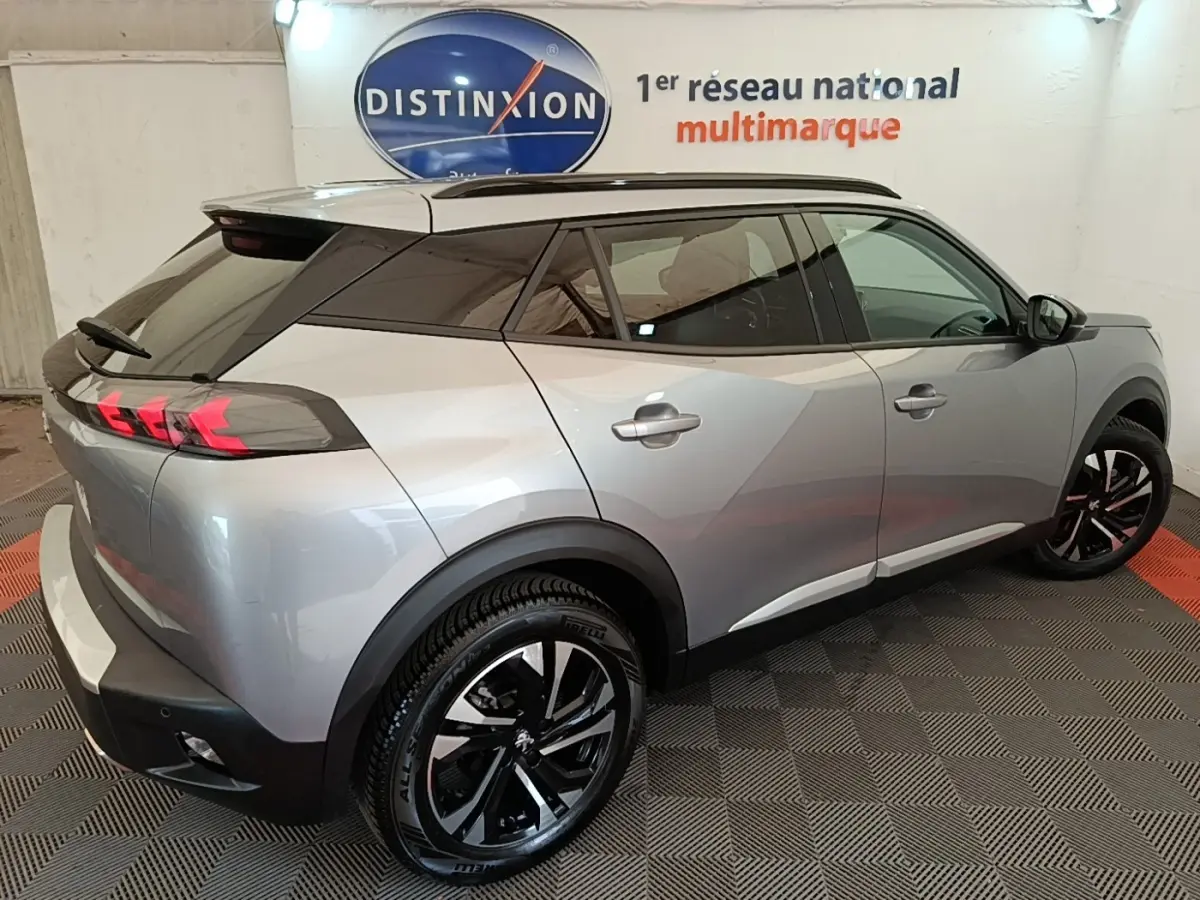 Vue 3/4 arrière droite d'un Peugeot 2008 gris clair 2022 avec jantes noires et feux arrière LED distinctifs.
