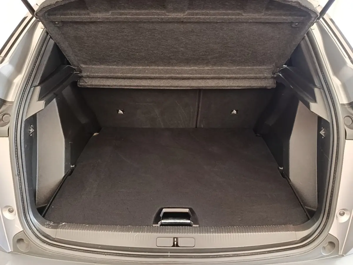 Coffre ouvert vu de l'arrière d'un Peugeot 2008 gris clair, montrant un espace de chargement propre et spacieux.