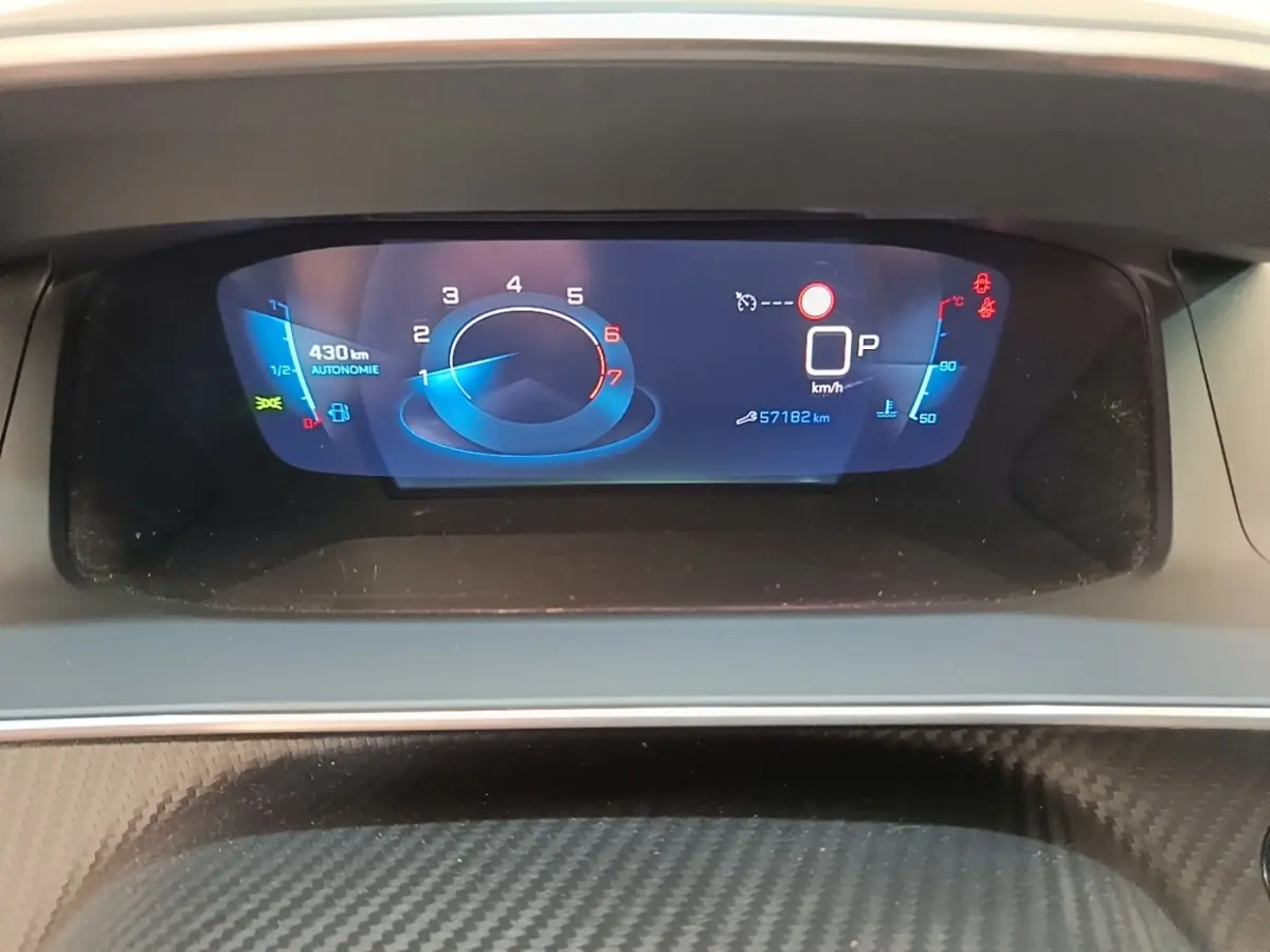 Gros plan sur le tableau de bord numérique du Peugeot 2008 gris clair, affichant la vitesse, autonomie et température moteur.
