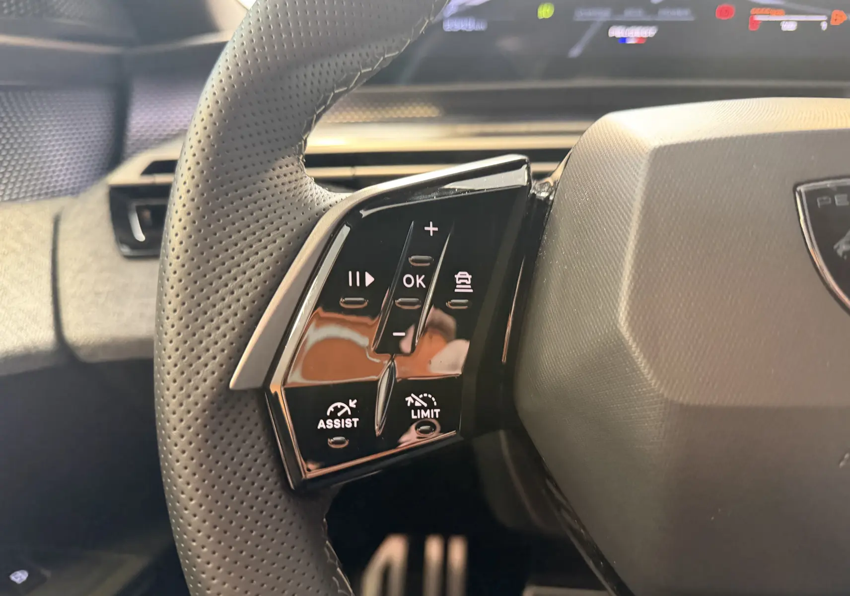 Gros plan sur les commandes à gauche du volant perforé du Peugeot 3008 Hybrid 145 GT, intérieur noir et gris.